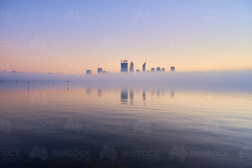 horizontal shot of Perth skyline at dawn with tiny buildings reflected on misty water - Australian Stock Image