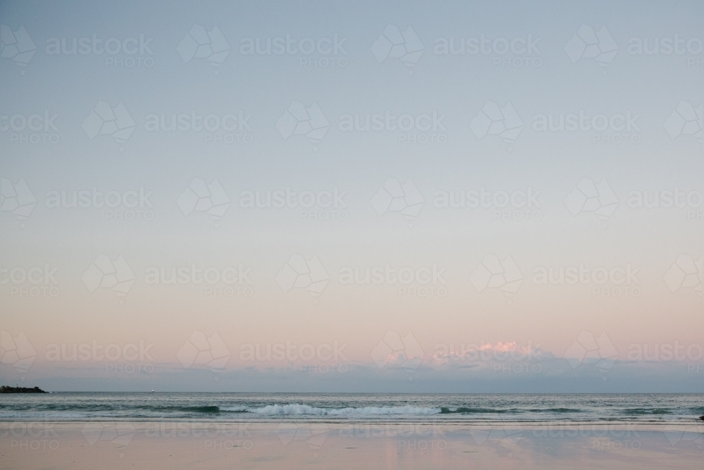 Horizontal shot of shoreline with beach waves at sunset - Australian Stock Image