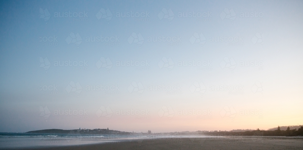 Horizontal shot of shoreline with beach waves at sunset - Australian Stock Image