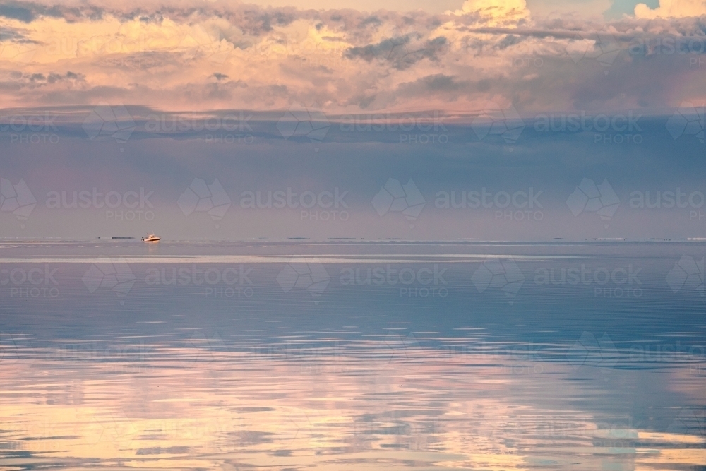 Horizontal shot of sunset clouds reflecting in the ocean - Australian Stock Image