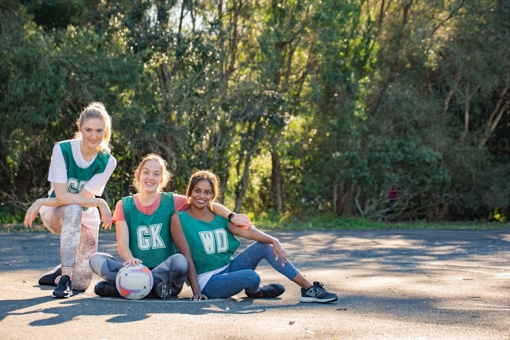 horizontal shot of three young smiling women in sports wear posing for a photo op on a sunny day - Australian Stock Image