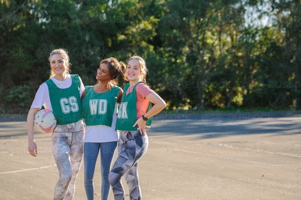 horizontal shot of three young women in sports wear posing for the camera on a sunny day - Australian Stock Image