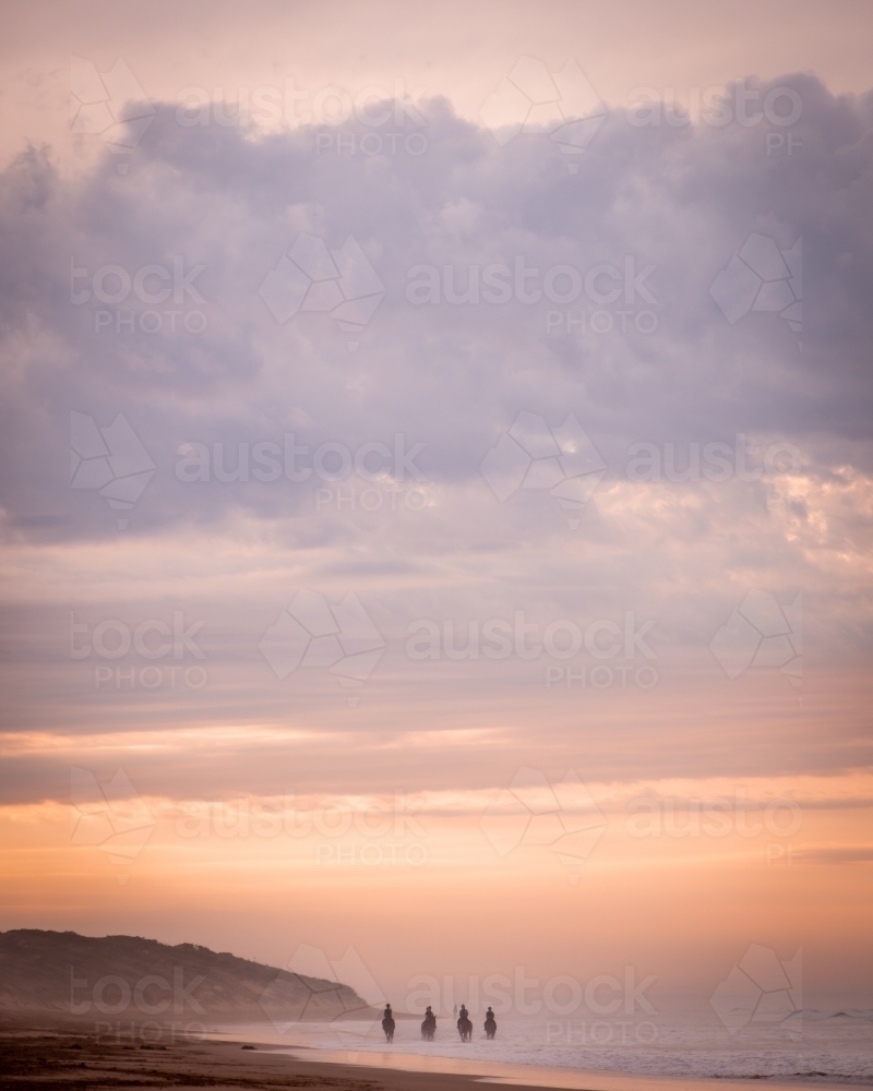 Horse Riding on a Beach at Sunrise - Australian Stock Image