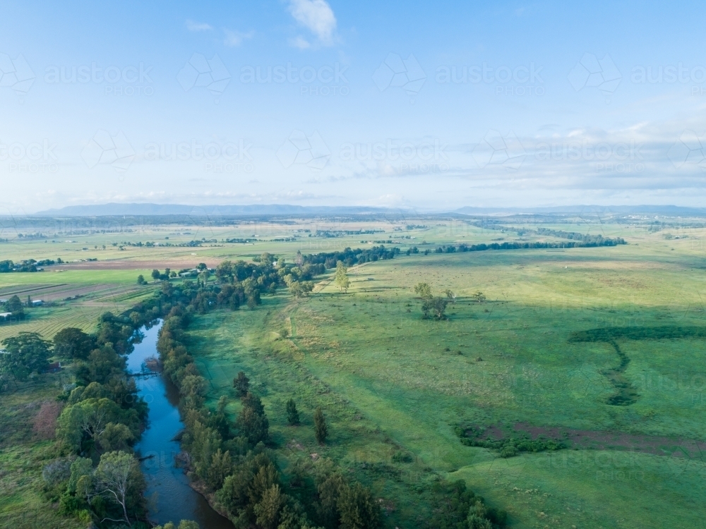 Hunter river in cool morning light at sunrise winding through green farm paddocks - Australian Stock Image