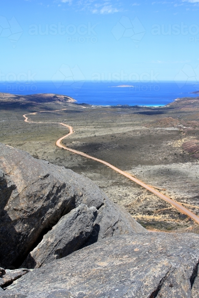 View along dirt road from top of granite peak - Australian Stock Image