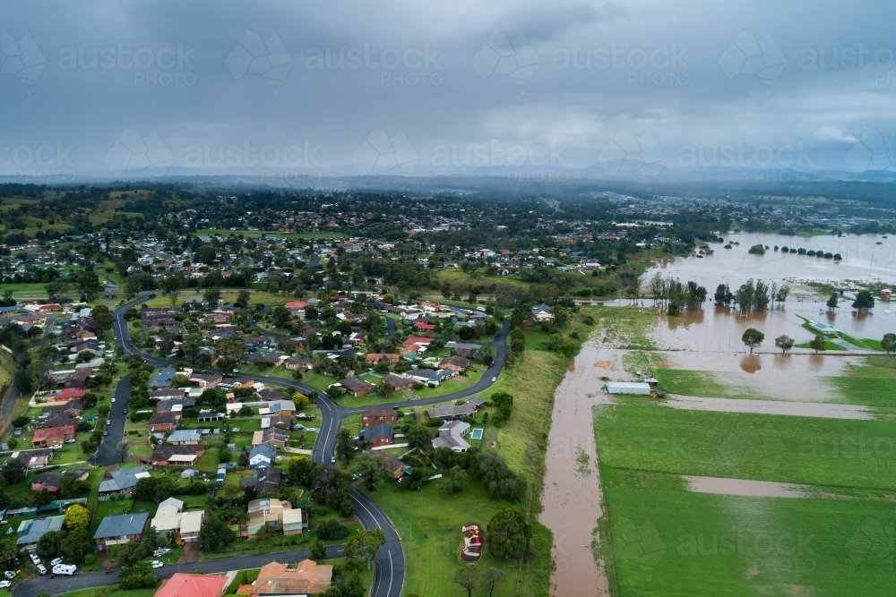 Incoming rain storm over houses in Darlington, Singleton with floodwaters cutting through paddock - Australian Stock Image