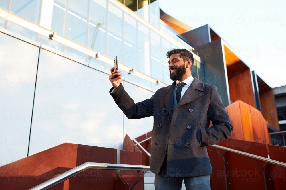 Indian businessman video conferencing outdoors in city - Australian Stock Image