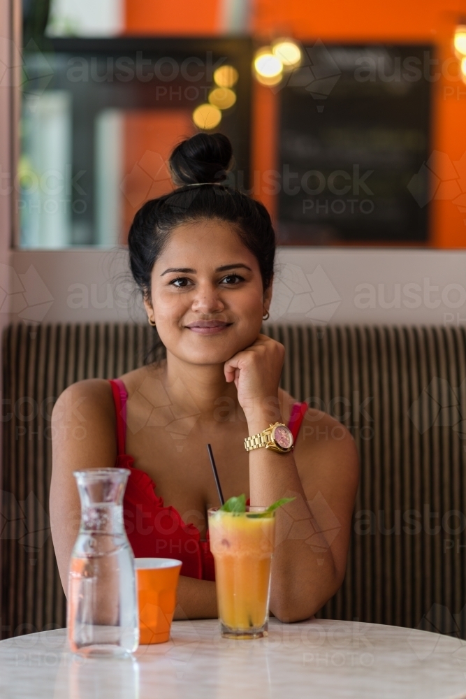 Indian woman in cafe with fruit smoothie - Australian Stock Image