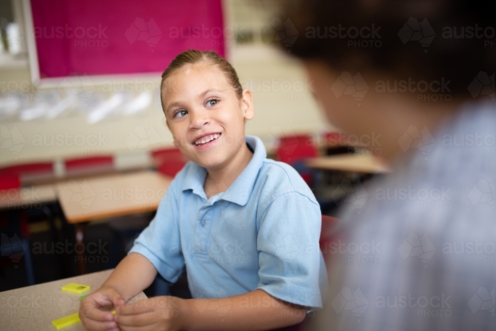 Indigenous girl student talking to a friend in a classroom - Australian Stock Image