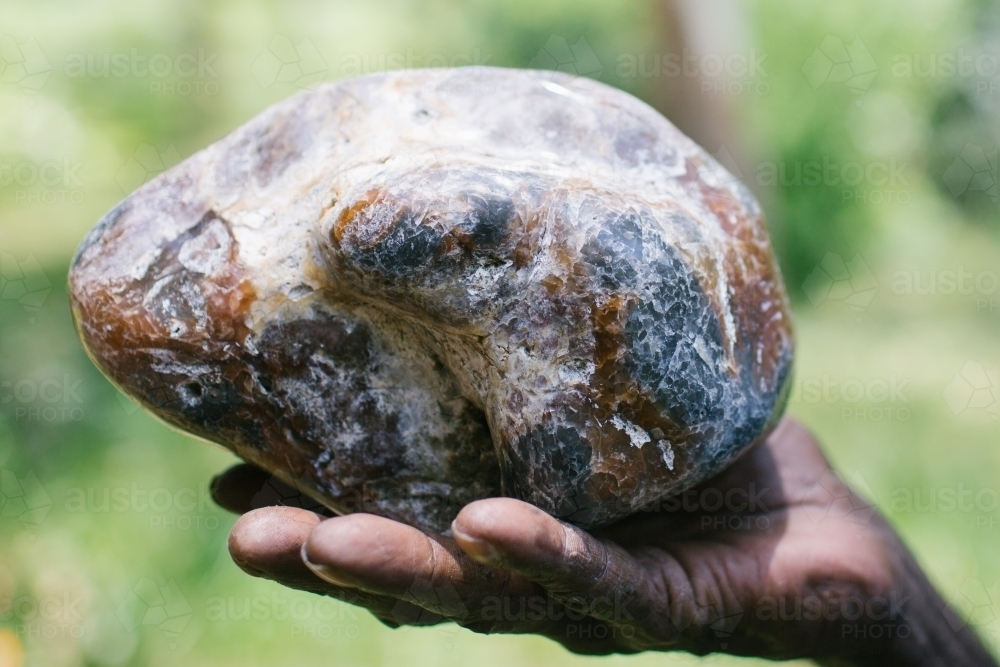 Indigenous hand holding stone - Australian Stock Image