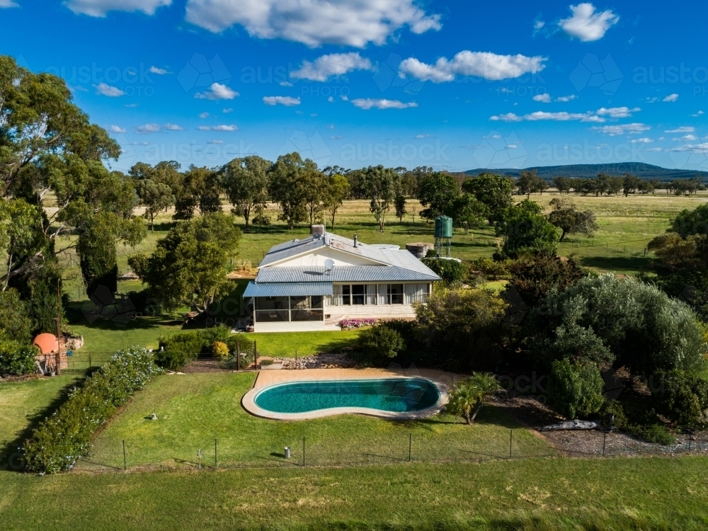 Inground swimming pool beside farm homestead house on property - Australian Stock Image