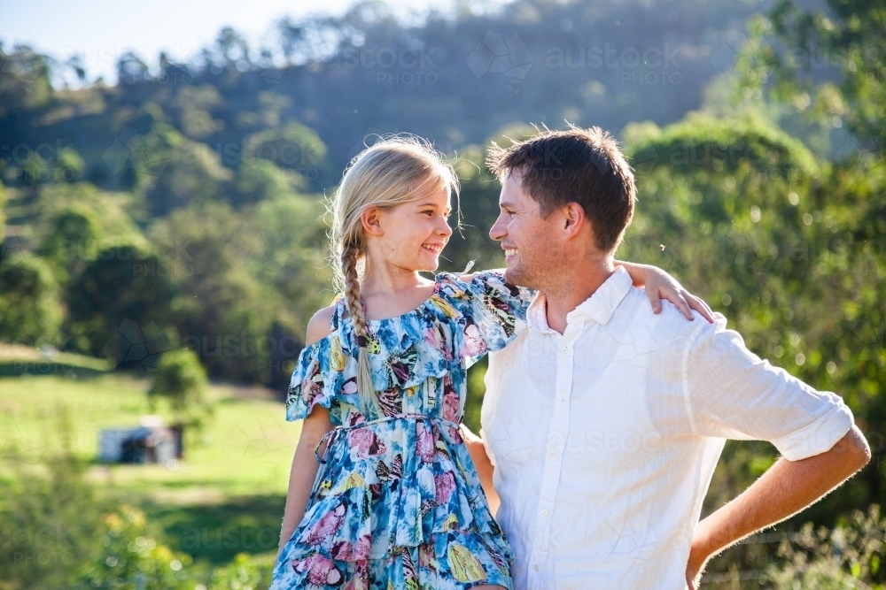 Intimacy or father and daughter looking at one another smiling outside on farm - Australian Stock Image