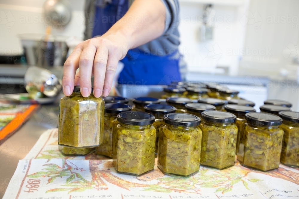 jars of pickle being filled in small commercial kitchen - Australian Stock Image