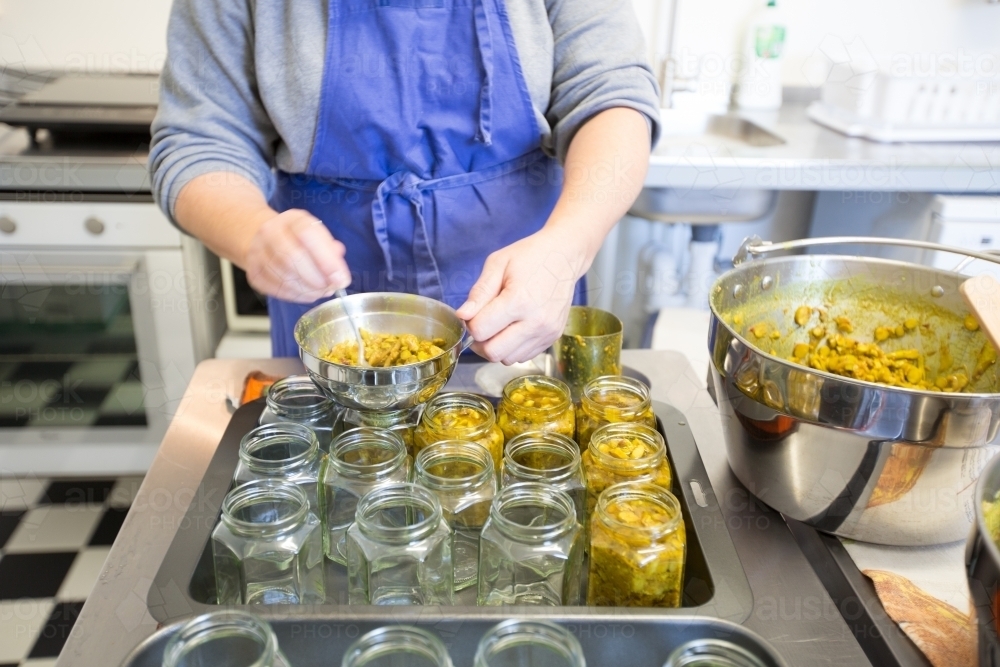 jars of pickle being filled in small commercial kitchen - Australian Stock Image