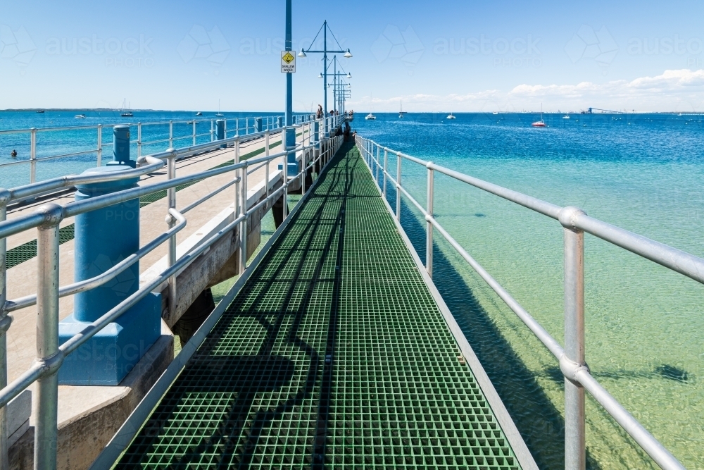 Jetty scene with people boats, blue sea and port in the distance - Australian Stock Image