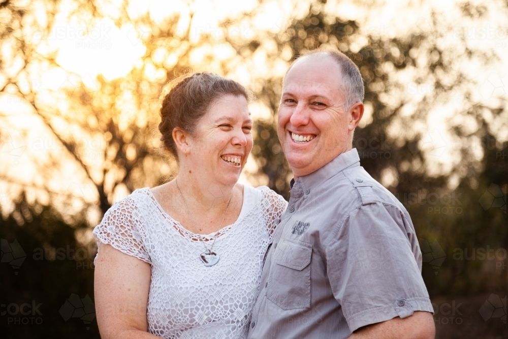 Joyful middle aged couple standing together in afternoon light - faithfulness - Australian Stock Image