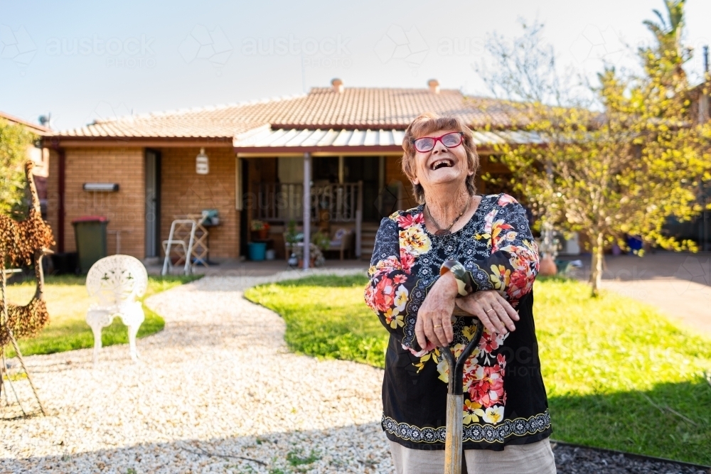 Joyful old woman laughing outside in garden - Australian Stock Image