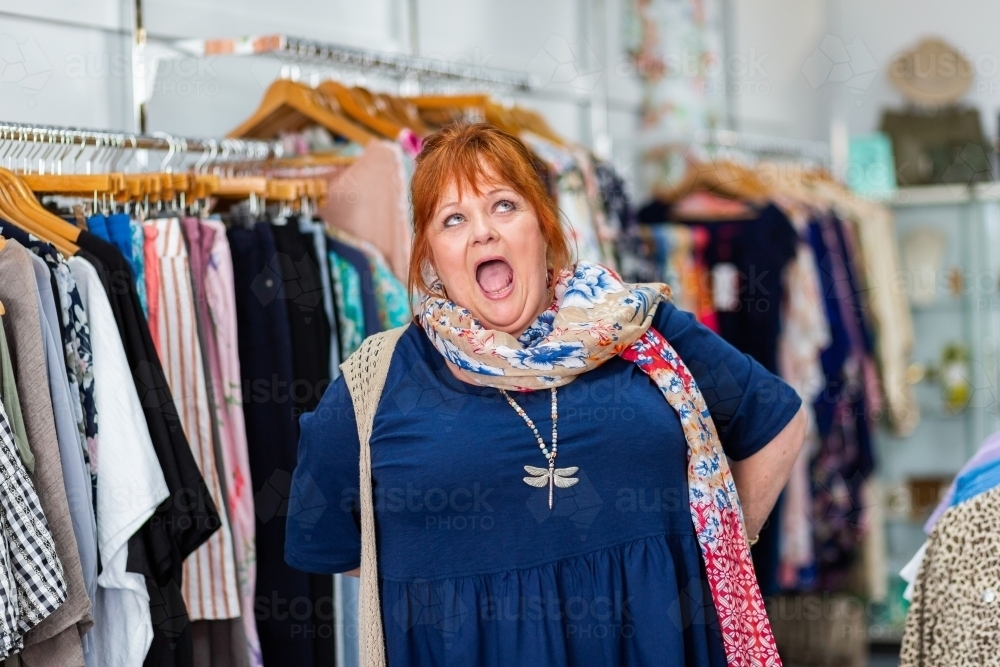 Joyful plus sized woman in clothing store with very happy expression - Australian Stock Image