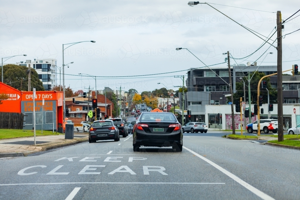 Keep clear sign on road with traffic stopped at lights in Melbourne suburb - Australian Stock Image