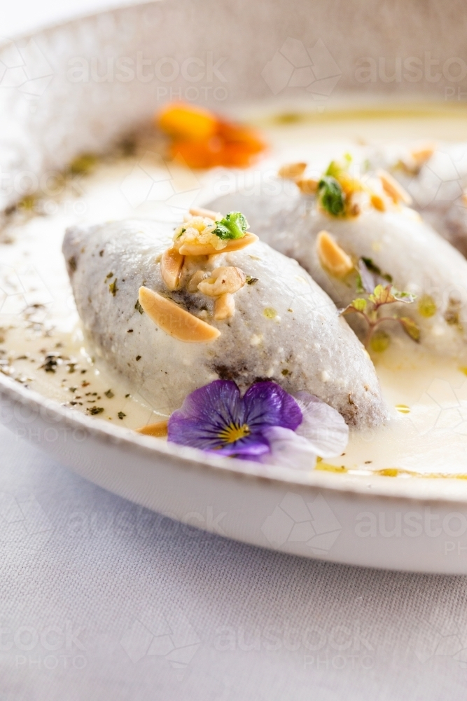 Kibbeh in creamy white sauce garnished with nuts and fresh herbs. - Australian Stock Image