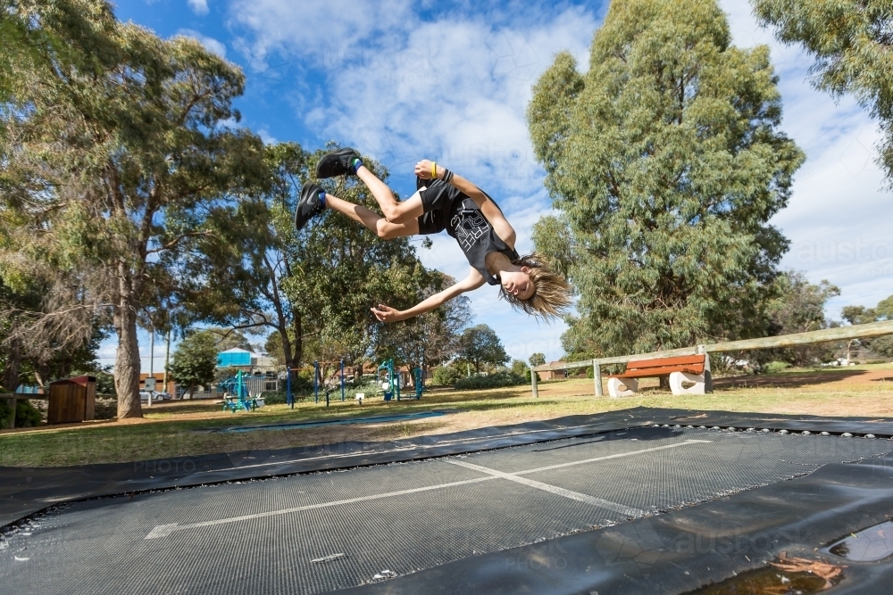 Kid upside down doing flip on trampoline - Australian Stock Image