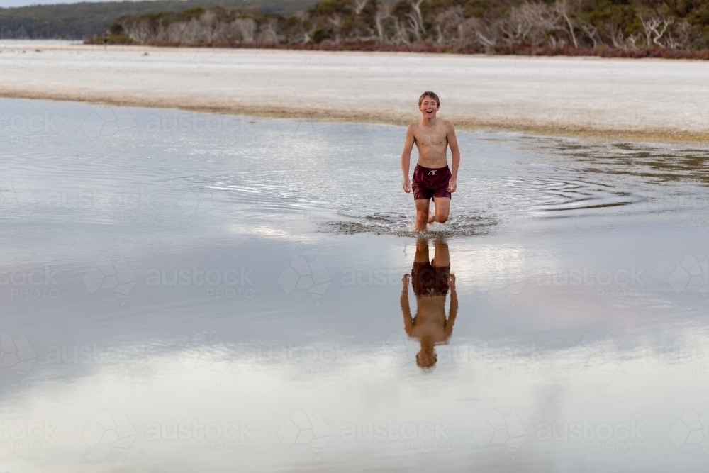 Kid wading through water in inlet - Australian Stock Image