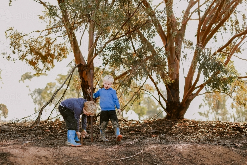 Kids exploring the bush in winter wearing blue gumboots - Australian Stock Image