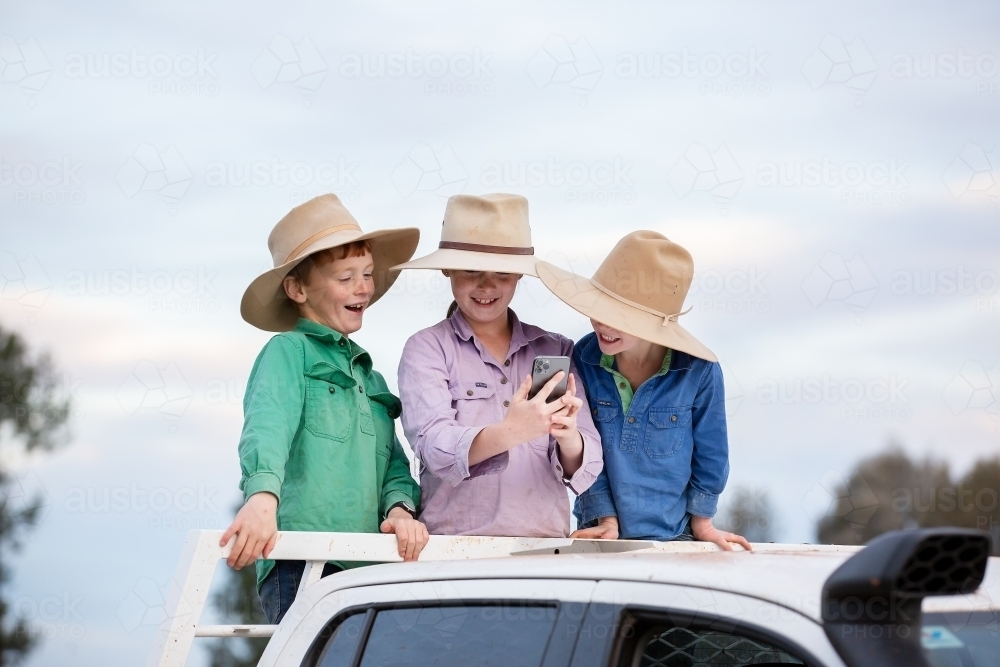 Kids on the back of a ute using a phone - Australian Stock Image