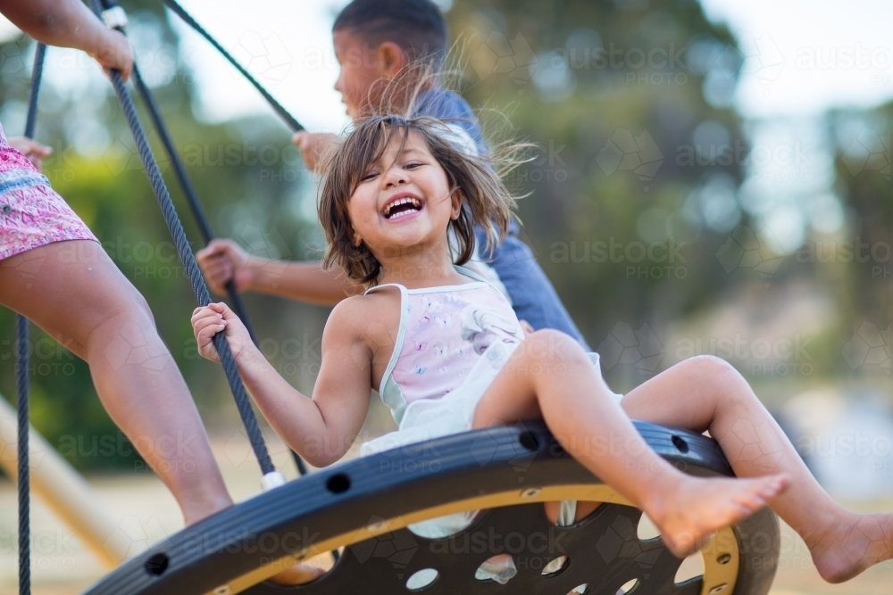 Kids playing on a swing in a playground - Australian Stock Image