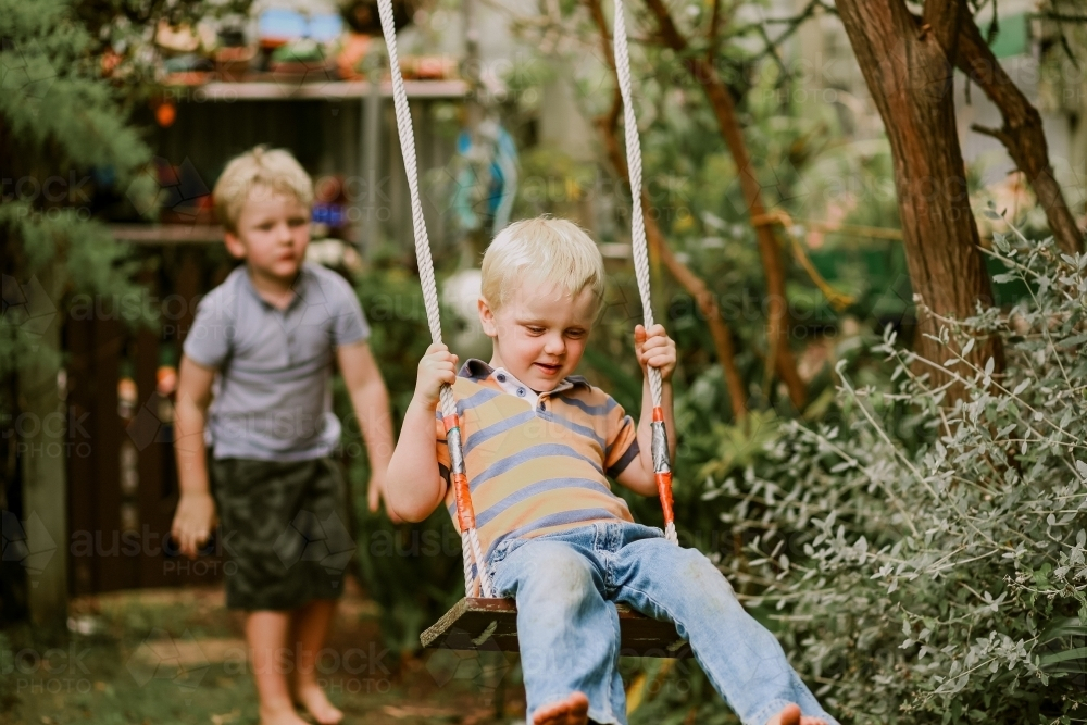 Kids playing on backyard swing - Australian Stock Image