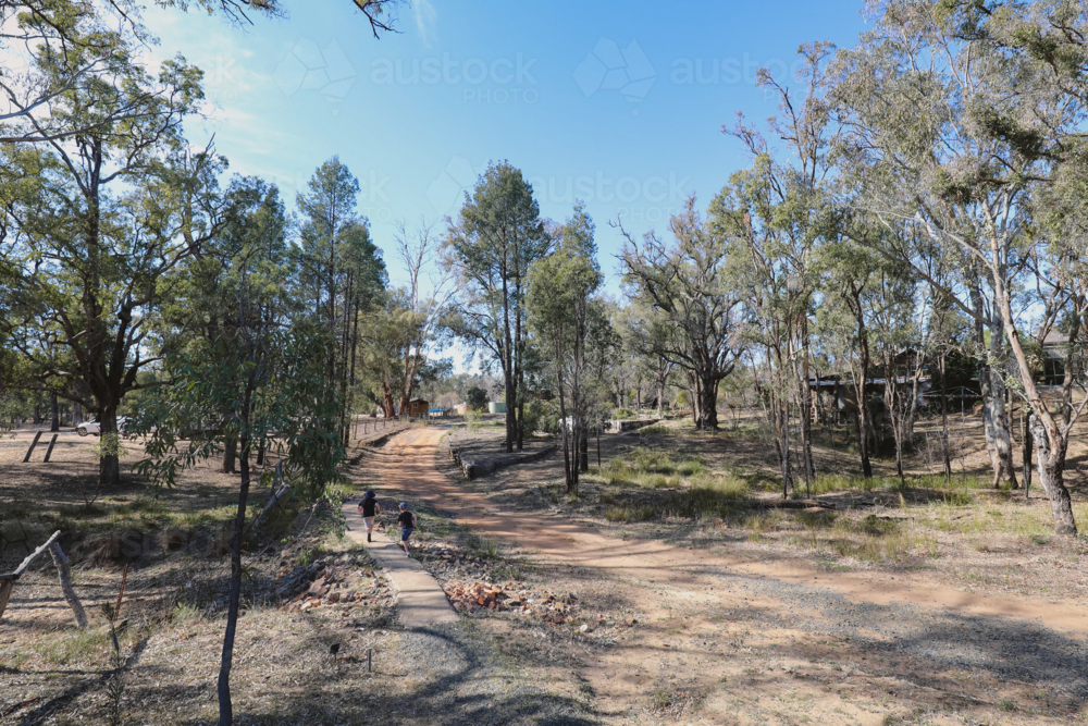 Kids running along footpath in rural Australia - Australian Stock Image