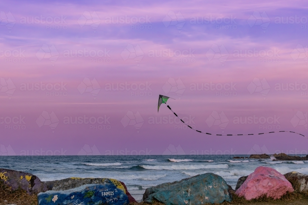 Kite flying over the Port Macquarie breakwall at sunset in pink sky - Australian Stock Image