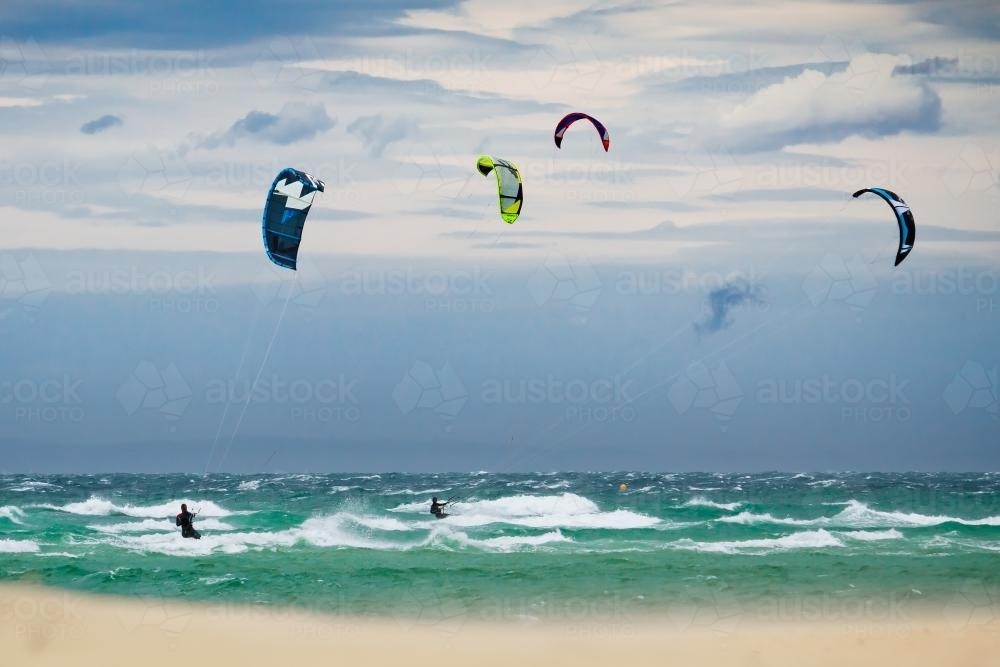 Kite surfers on the water with storm clouds behind. - Australian Stock Image