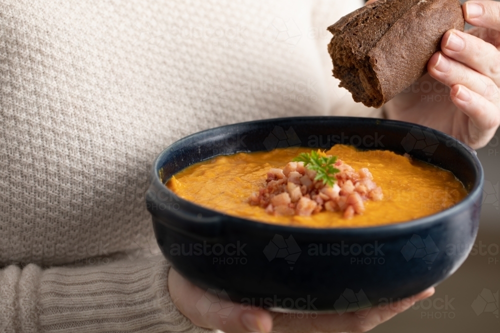 Lady holding bowl of soup with rye bread - Australian Stock Image