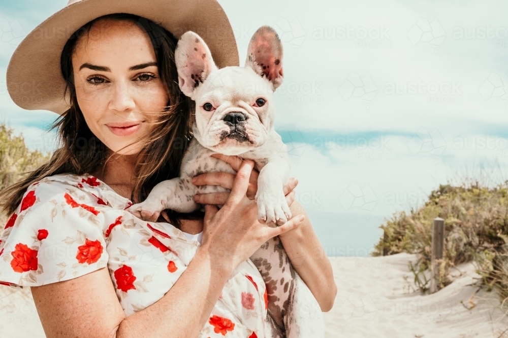 Lady smiles with her cute french bulldog puppy. - Australian Stock Image