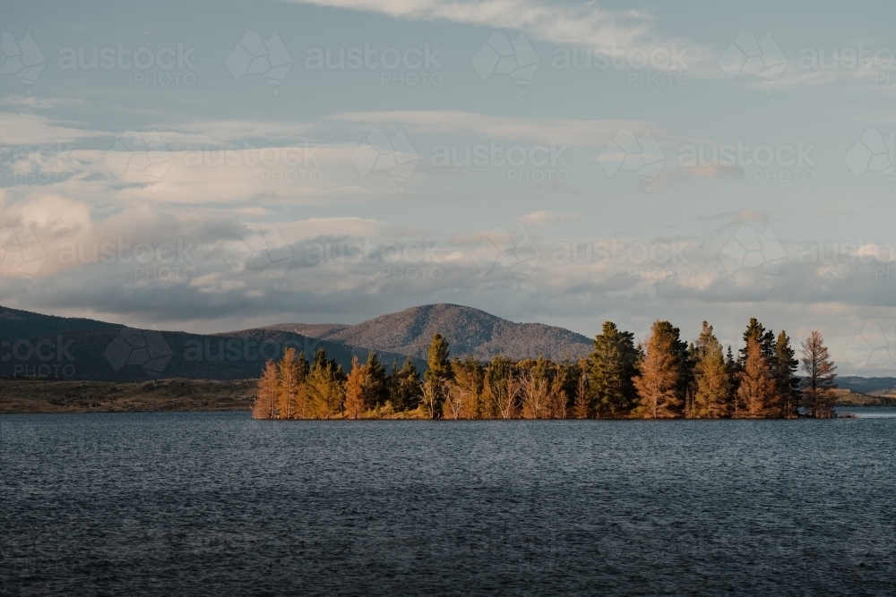 Lake Jindabyne at sunset with autumn coloured trees and mountains - Australian Stock Image