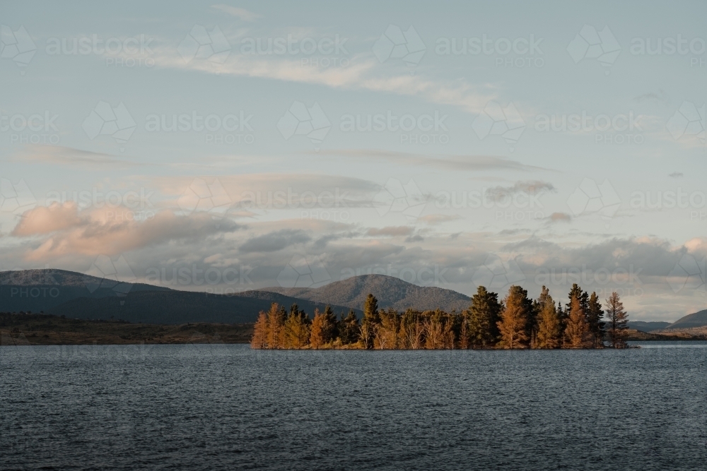 Lake Jindabyne at sunset with autumn coloured trees and mountains - Australian Stock Image