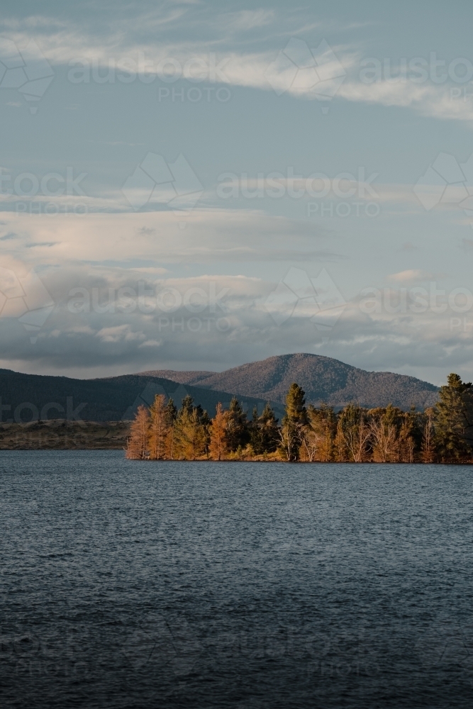 Lake Jindabyne at sunset with autumn coloured trees and mountains - Australian Stock Image