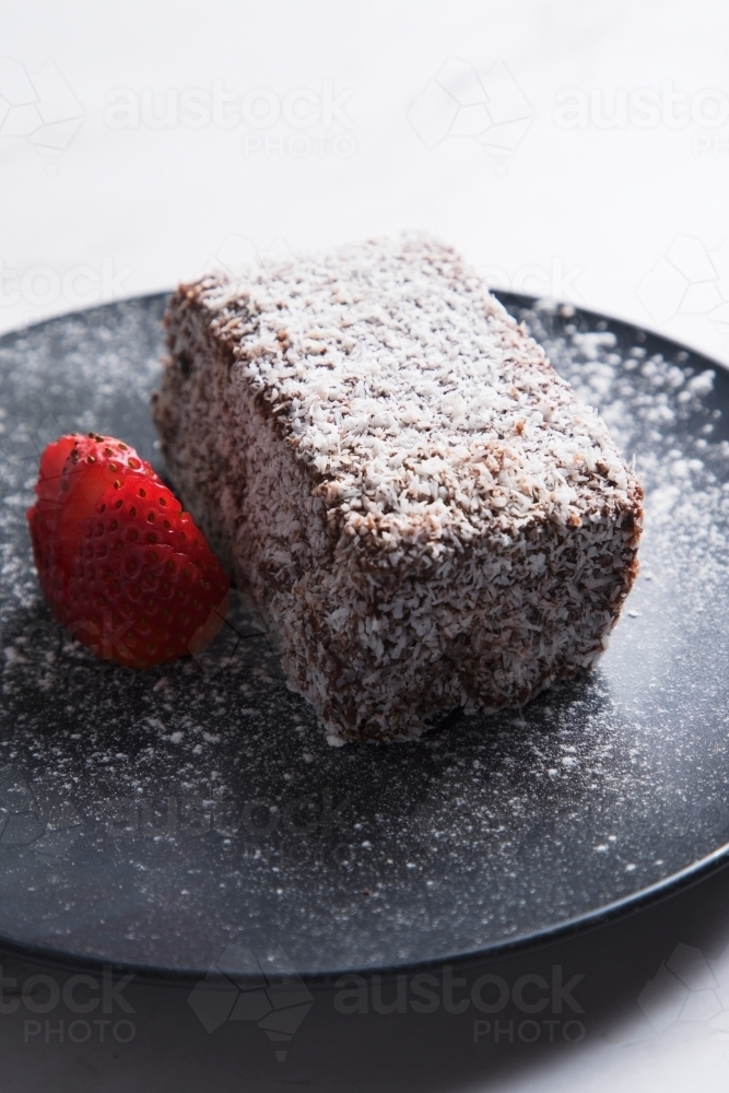 Lamington with sliced strawberry on plate - Australian Stock Image