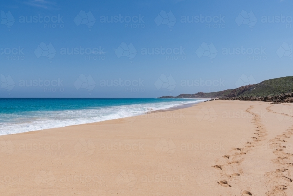 Landscape view looking along sandy beach with footprints in sand - Australian Stock Image