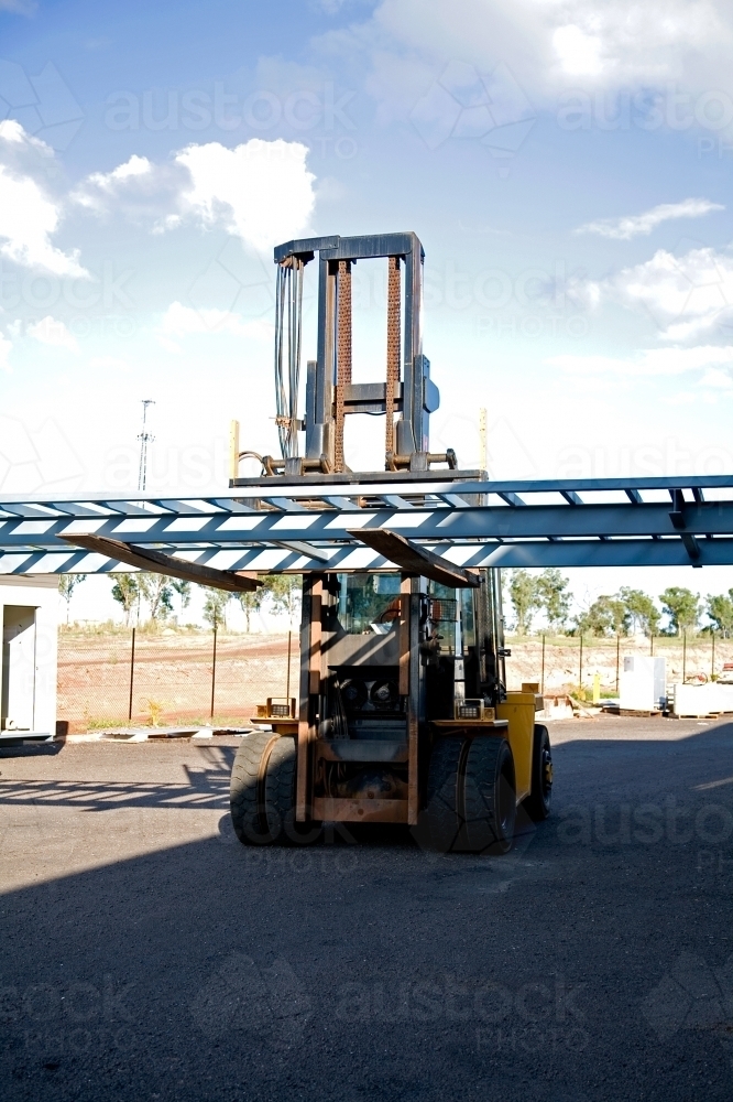 Large forklift carrying metal framework on a work site - Australian Stock Image
