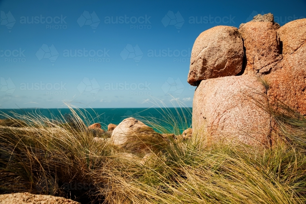 Large, rounded boulders behind the tall grasses - Australian Stock Image