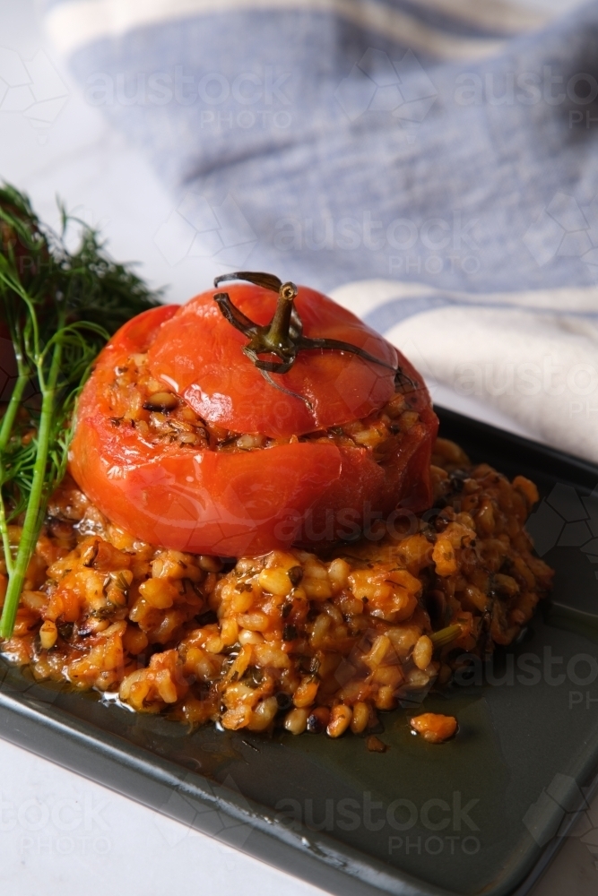 large tomatoes stuffed with rice and green garnish on top - Australian Stock Image