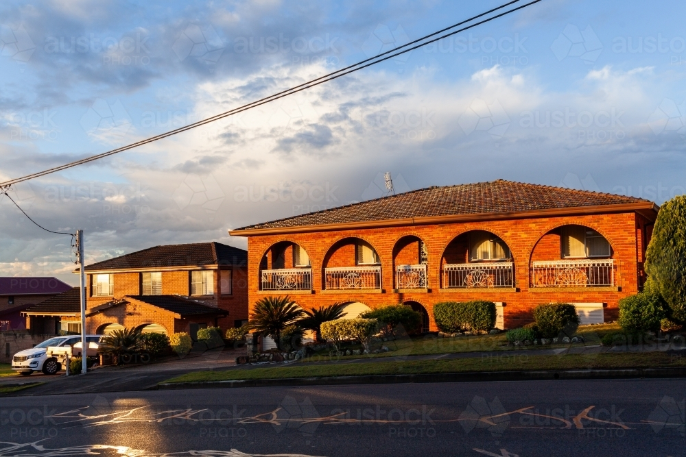 Last sunset light on brick houses along street in Wallsend Newcastle with powerline overhead - Australian Stock Image