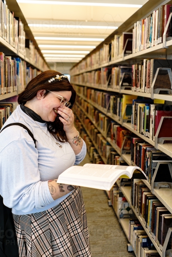 Image of Laughing Student With Open Book in Library - Austockphoto