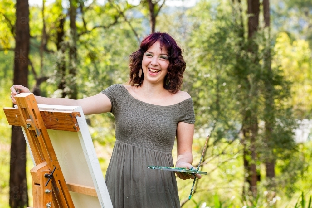 laughing teenage artist painting outside - Australian Stock Image