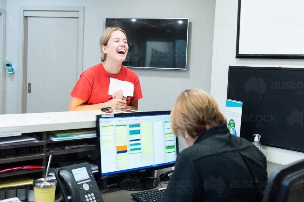 Laughing women in dental reception room with receptionist - Australian Stock Image