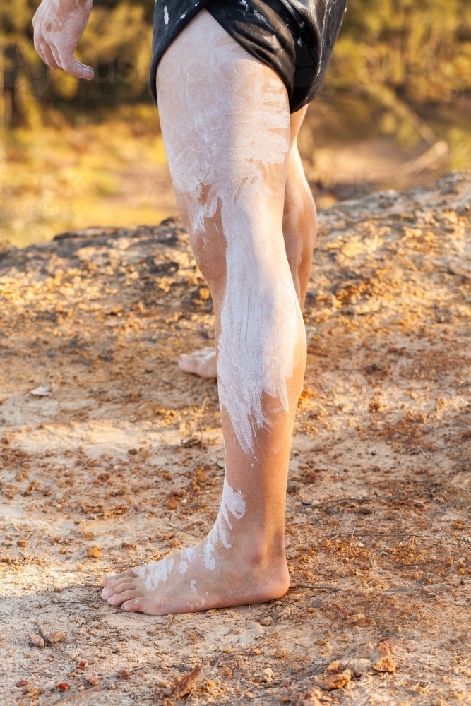 legs of aboriginal man standing on cliff - Australian Stock Image