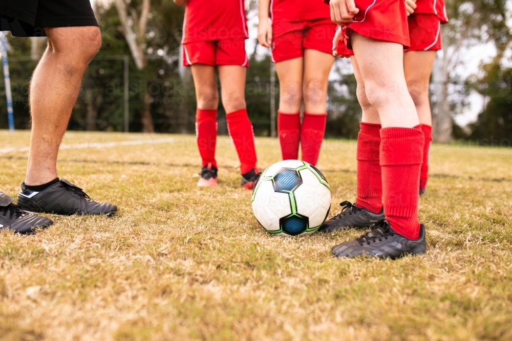 Legs view of a tween girls football team training together at a sports oval - Australian Stock Image