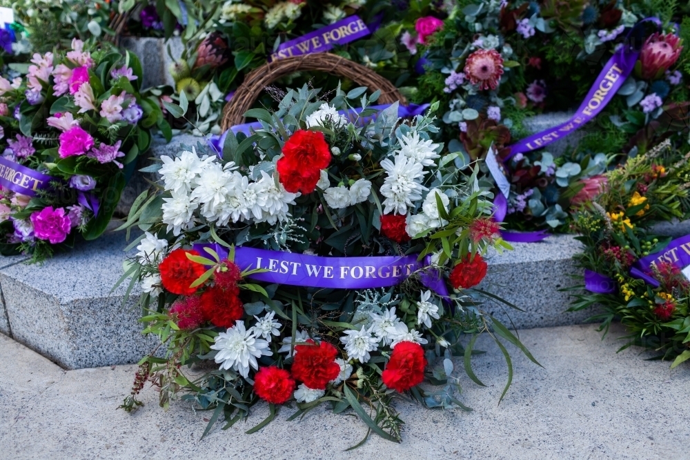 Lest we forget written on purple ribbon on ANZAC day wreath at war memorial - Australian Stock Image